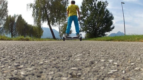 Boy riding on a white hoverboard, on a small road in the countryside Stock Footage 103599663
