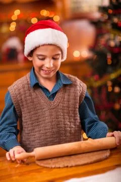 Boy with rolling pin baking in kitchen Christmas cakes Stock Photos