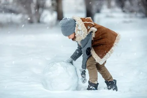 Boy is rolling snow ball for making a snowman. Stock Photos