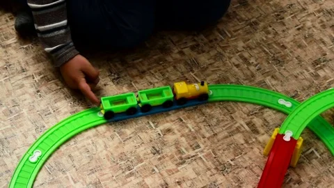 The boy is rolling a train on a toy railway Stock Footage 75560586
