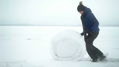 Boy rolls big snow ball for snowman in winter. Stock Footage 101075609