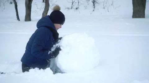 Boy rolls big snow ball for snowman in winter. Stock Footage 101210818