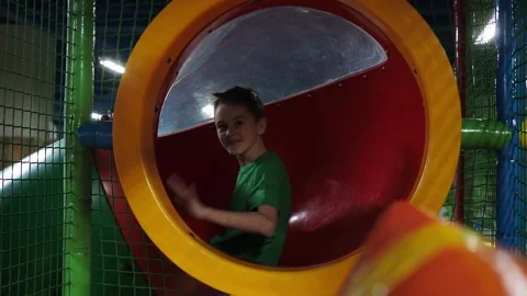 The boy rolls into a children's slide- pipe. he waves his hand. children's Stock Footage 171067556
