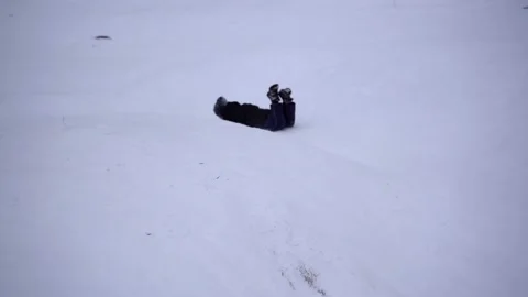 The boy rolls down the snowy slope on an ice rink, a sled. Winter fun Stock Footage 219999807