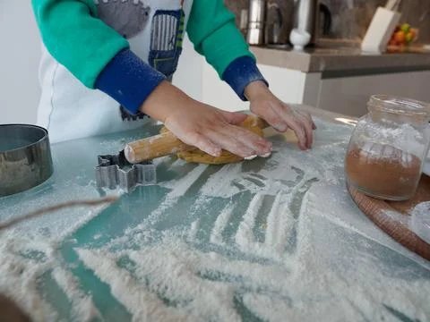 Boy rolls out shortbread dough for christmas cookies with a wooden rolling pin Stock Photos
