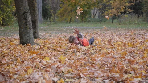Boy rolls through the autumn fallen leaves. Stock Footage 141081995