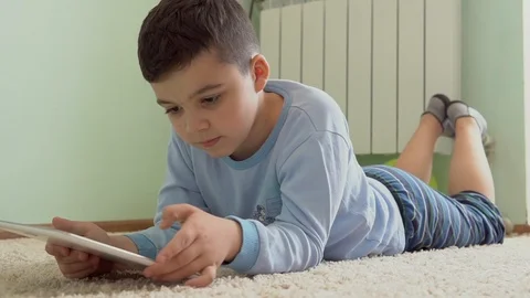 The boy in the room is playing on the tablet Stock Footage 89210590