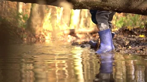 Boy in rubber boots plays with shovel in the creek in the forest Stock Footage 82107653