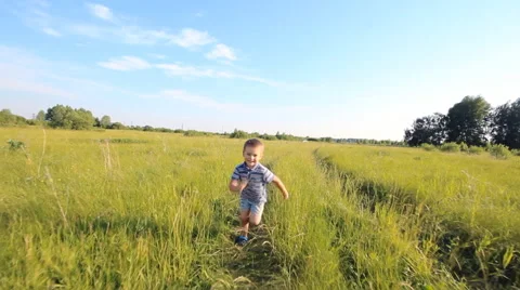 Boy running across hill in slowmotion Stock Footage