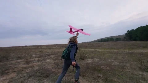 Boy running across an open field and launching a toy airplane 库存影片 323224333