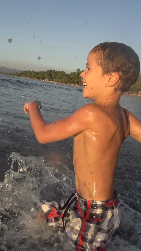 Boy running and jumping fast into the sea water. Vertical, Social Media Stock Footage 121338955