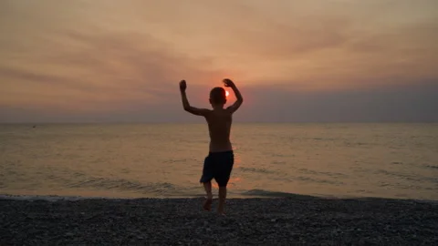 Boy Running and Jumping into Sea at Sunset Stock Footage 307321156