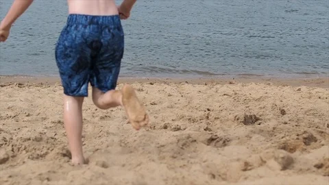 Boy running on the beach and jumping in the lake, slow motion video Stock Footage 93502438