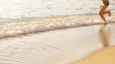 Boy is running on the beach, raises splashes. Slow Motion Stock Footage 82187681