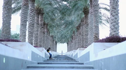 Boy running down the stairs with palm trees on the sides Stock Footage 68639635
