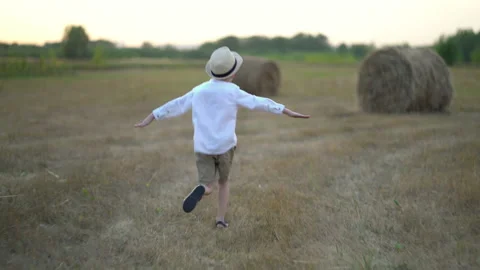 Boy running in a field with haystacks Stock Footage 159904442