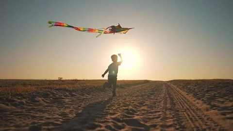 Boy running with kite at sunset. Child enjoying freedom in nature flying kite Stock Footage 316720393