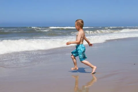 Boy running into the ocean Stock Photos