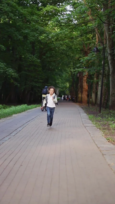 Boy running in park on sunny spring evening, run along the road. Active life Stock Footage 320252624