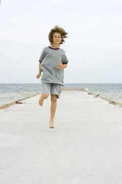 Boy running on pier, front view Stock Photos
