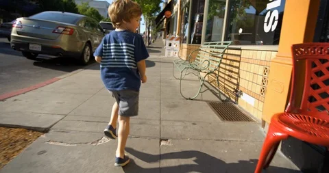 Boy running on the sidewalk in town 스톡 동영상 88372423