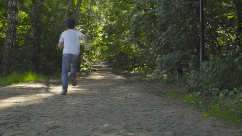 A boy running through alley in the park Stock Footage