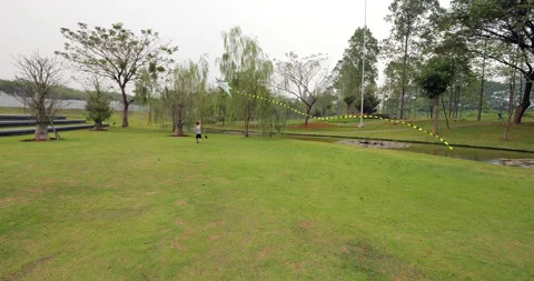 Boy running through green park, flying large kite on short line, slow motion 库存影片 322045677