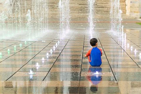Boy running through water streams in street fountain Stock-Fotos