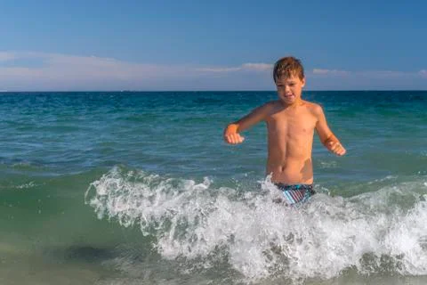 Boy running through the waves at the beach Stock Photos