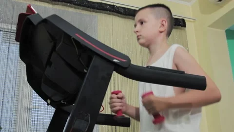Boy running on a treadmill with dumbbells in his hands Stock Footage 200975344