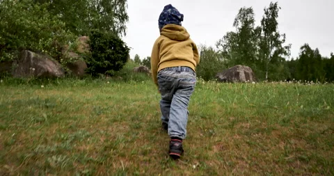 Boy is running uphill through the green grass. toddler is running up the hill. Stock Footage 243416450