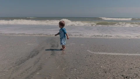 Boy running from wave on the beach Stock Footage 128614753