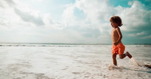 Boy running on the waves in summer warm day with smile and laugh Vídeo Stock 237758801