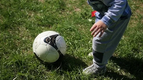 The boy runs across the grass and kick the ball. Outdoor Sports. Football 库存影片 75913020
