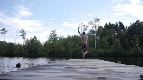 Boy runs and jumps off dock into water Stock Footage 68655585