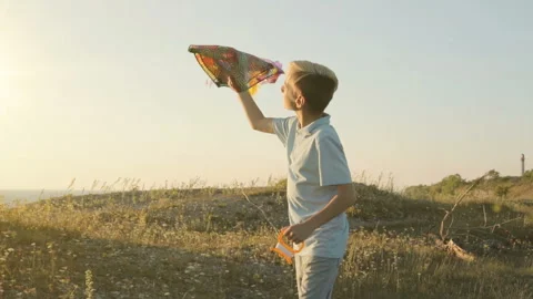 The boy runs and tries to launch a kite in the sky in a strong wind Stock-Footage 89878657