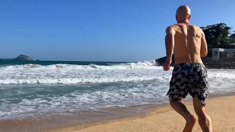 A boy runs on the beach and throws water into the sea Stock Footage 305153782