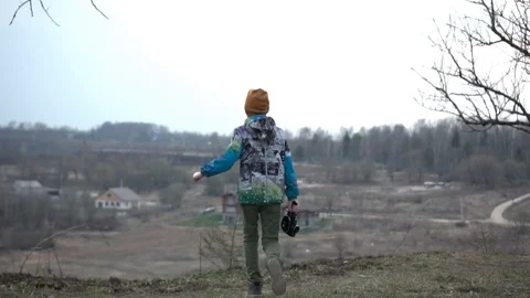 The boy runs to the cliff above the river with a movie camera in his hand Stock Footage 128330224