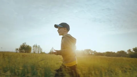 The boy runs through the green grass holding his tablet in his hands. Stock Footage 243513759