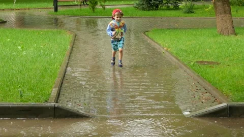 The boy runs through the puddle in the rain. Stock Footage 86149829