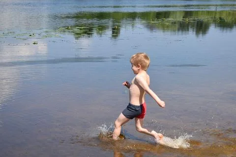 The boy runs into the water. Stock Photos