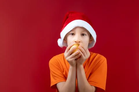 A boy in a Santa hat on a red background Stock-Fotos