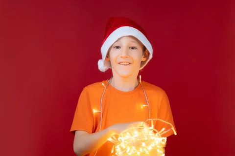 A boy in a Santa hat on a red background Stock Photos