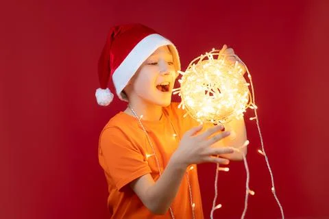 A boy in a Santa hat on a red background Stock Photos