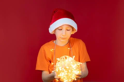 A boy in a Santa hat on a red background Stock Photos