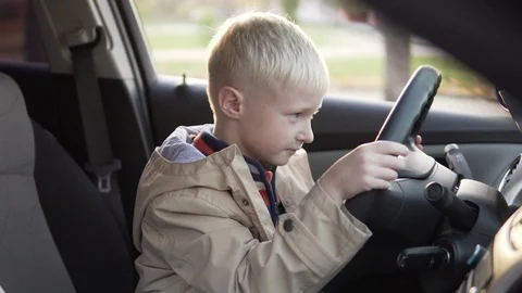 The boy sat in the driver's seat in the car. Stock Footage 96983761