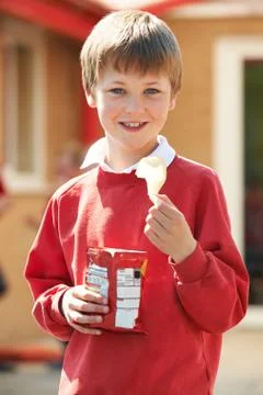 Boy In School Uniform Eating Potato Chip In Playground Stock Photos