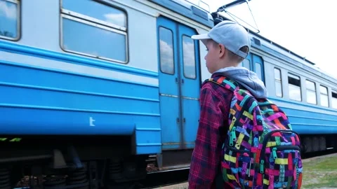 A boy, a schoolboy with a backpack, stands on the platform and looks at the Video stock 196945453