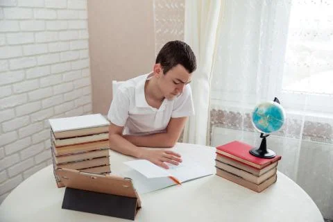 A boy schoolboy does his homework. Textbooks and notebooks on the table Stock Photos