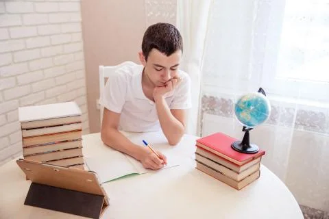A boy schoolboy does his homework. Textbooks and notebooks on the table Stock Photos